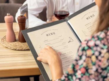 Frau hält Speisekartenmappe in Restaurant in der Hand