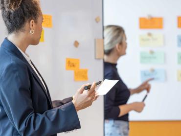 Zwei Kolleginnen arbeiten agil an Whiteboards