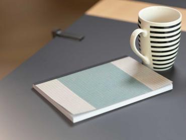 Notizbuch und Kaffeetasse auf Schreibtisch