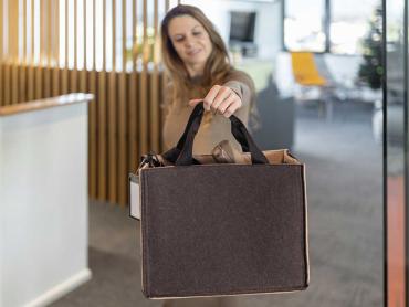 Frau hält Desk Sharing Bag braun/beige in den Händen
