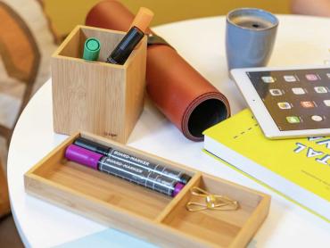 Schreibtisch-Accessoires Eyestyle aus Bambus steht auf Tisch neben einrollbarer Schreibunterlage, Tablet und Buch