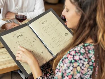 Frau blickt in Speisekarte im Restaurant