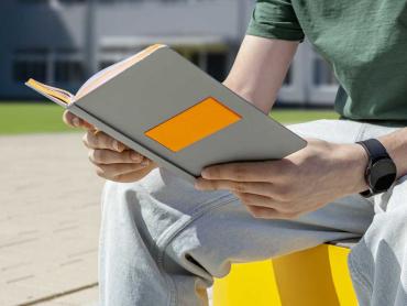 Junger Mann hält Linescape Neo Notizbuch in grau in den Händen