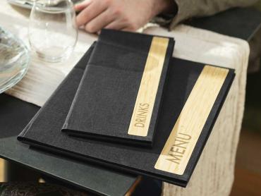Speisekarten-Mappen mit Bambuseinsatz liegen auf gedecktem Tisch in Restaurant