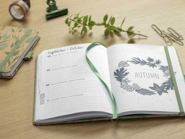 Zwei Jolie Kalender der Serie Pure mit Kraftpapier-Cover im Leaves-Design liegen nebeneinander auf einem Tisch
