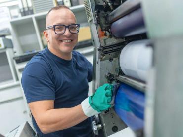 Mann trägt blaue Farbe auf Druckwalze auf