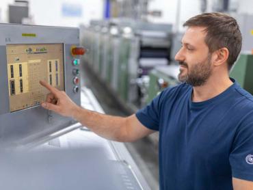 Mann bedient Terminal von Druckmaschine