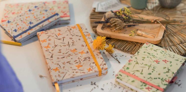 Notizbücher und Notizblöcke mit floralem Muster liegen auf Tisch