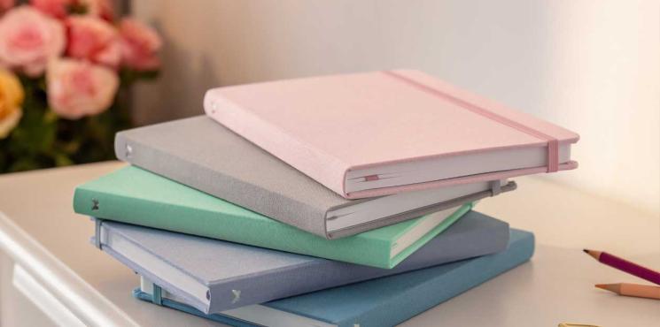 Notizbücher liegen als Stapel auf Tisch