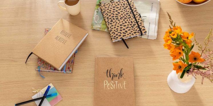 Notizbücher sind auf Tisch angeordnet mit Blumen und Kaffeetasse