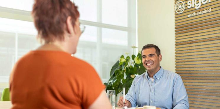 Zwei Kollegen unterhalten sich amüsiert in Einzelgespräch