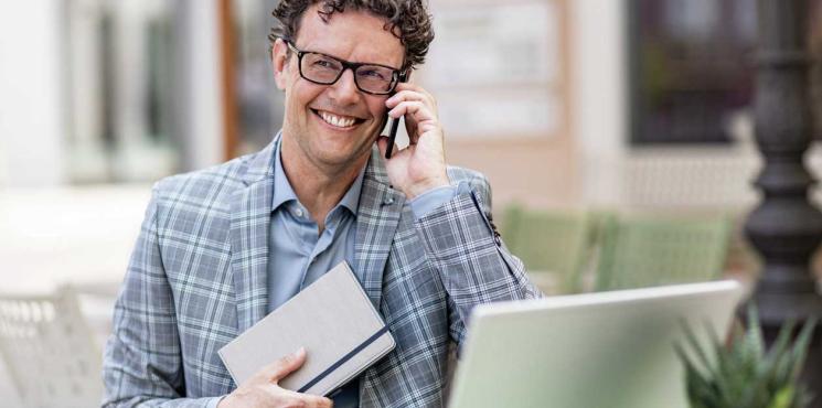 Angestellter telefoniert am Smartphone mit Notizbuch in der Hand