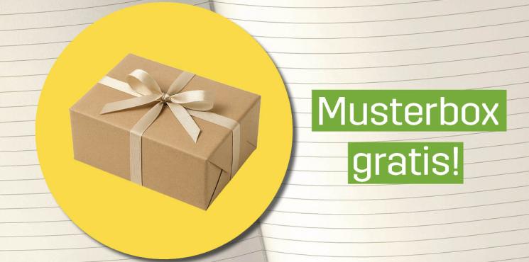 Gelber Button mit Musterbox aus Karton, im Hintergrund Lineatur von Notizbuch