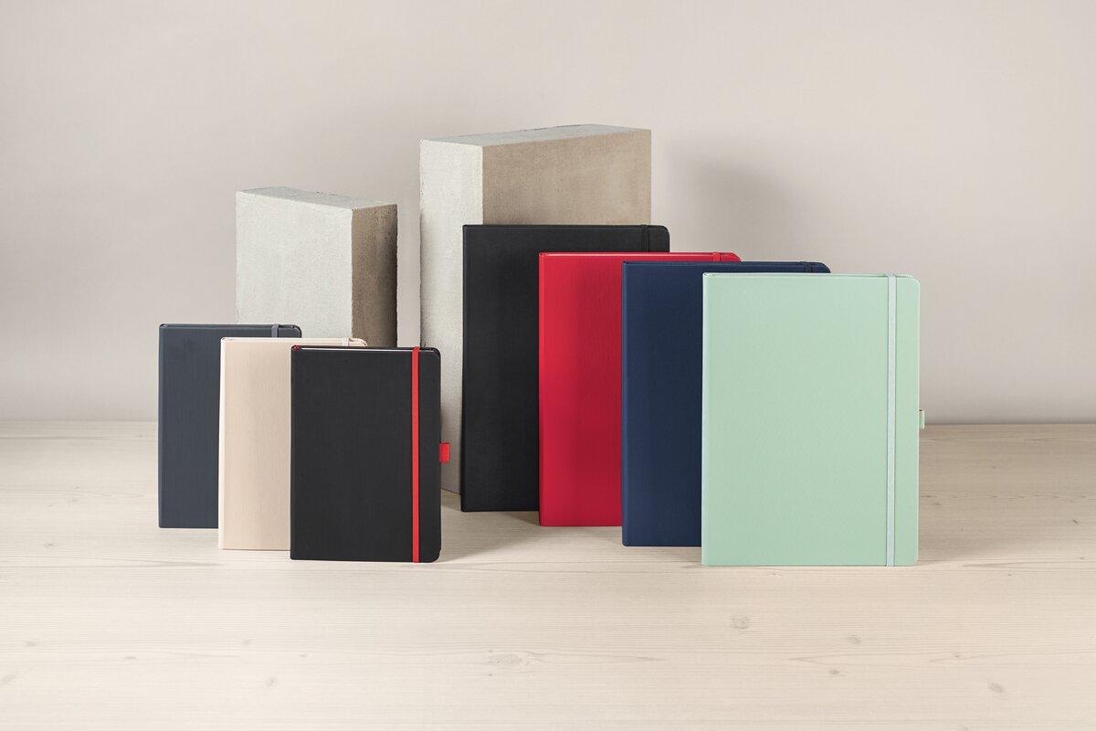 Notizbücher in verschiedenen Farben vor Betonblöcken