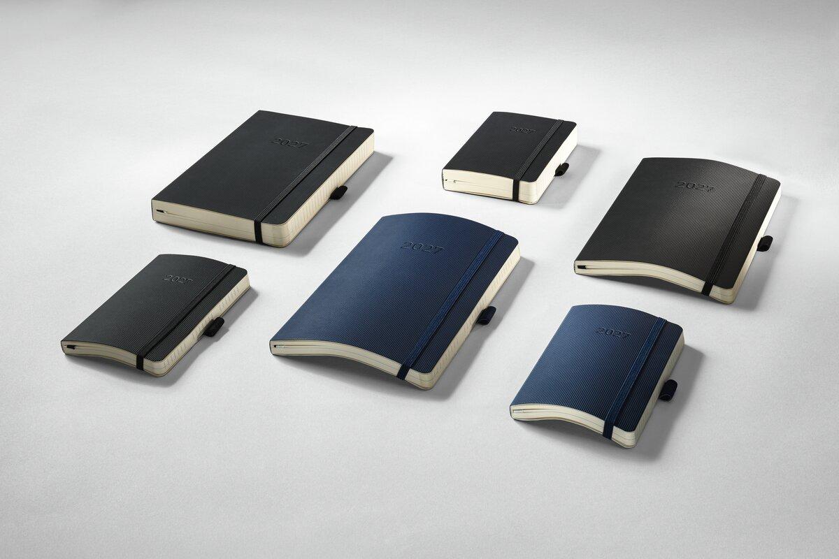 Das Bild zeigt mehrere Conceptum Kalender 2027 in Schwarz und Blau in verschiedenen Formaten arrangiert