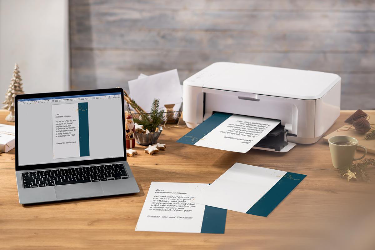Laptop and printer on desk Christmas decoration and printed document