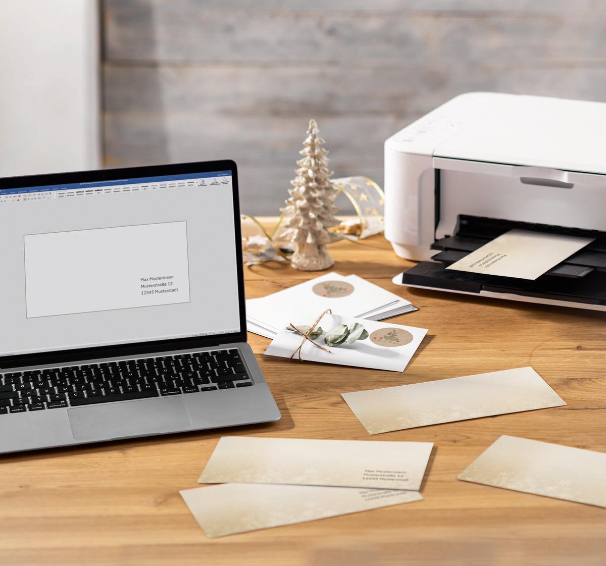 Laptop near printer on desk, Christmas cards are created