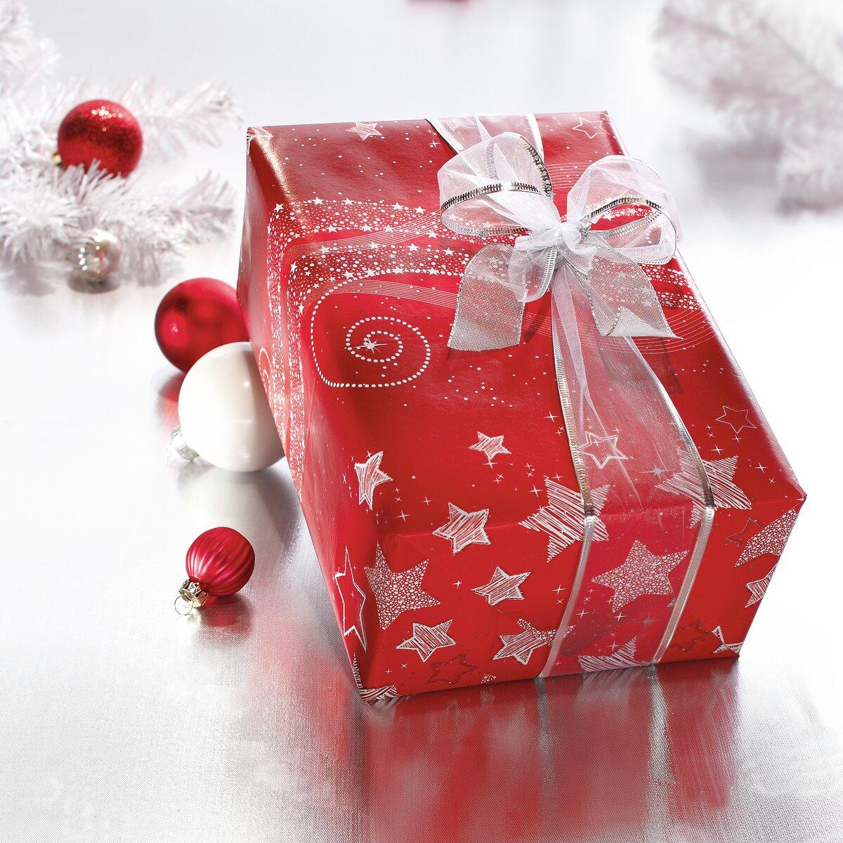 Rot eingepacktes Geschenk mit Schleife, umgeben von roten und weißen Weihnachtskugeln