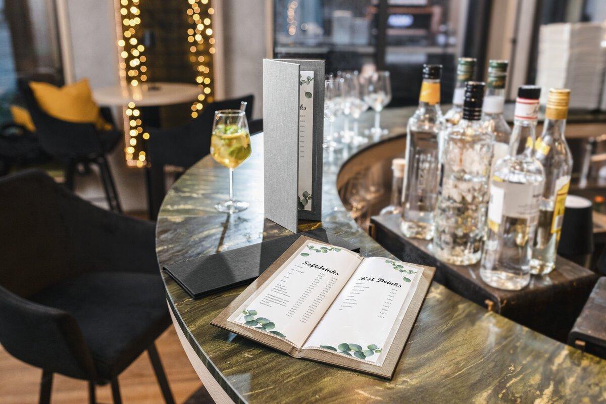 Getränkekarte auf einer Theke Cocktailglas und Flaschen im Hintergrund