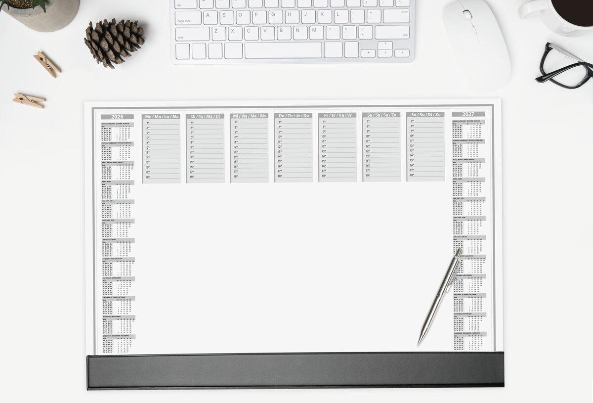 Schreibtisch mit Kalender, Tastatur, Maus, Brille und Tasse