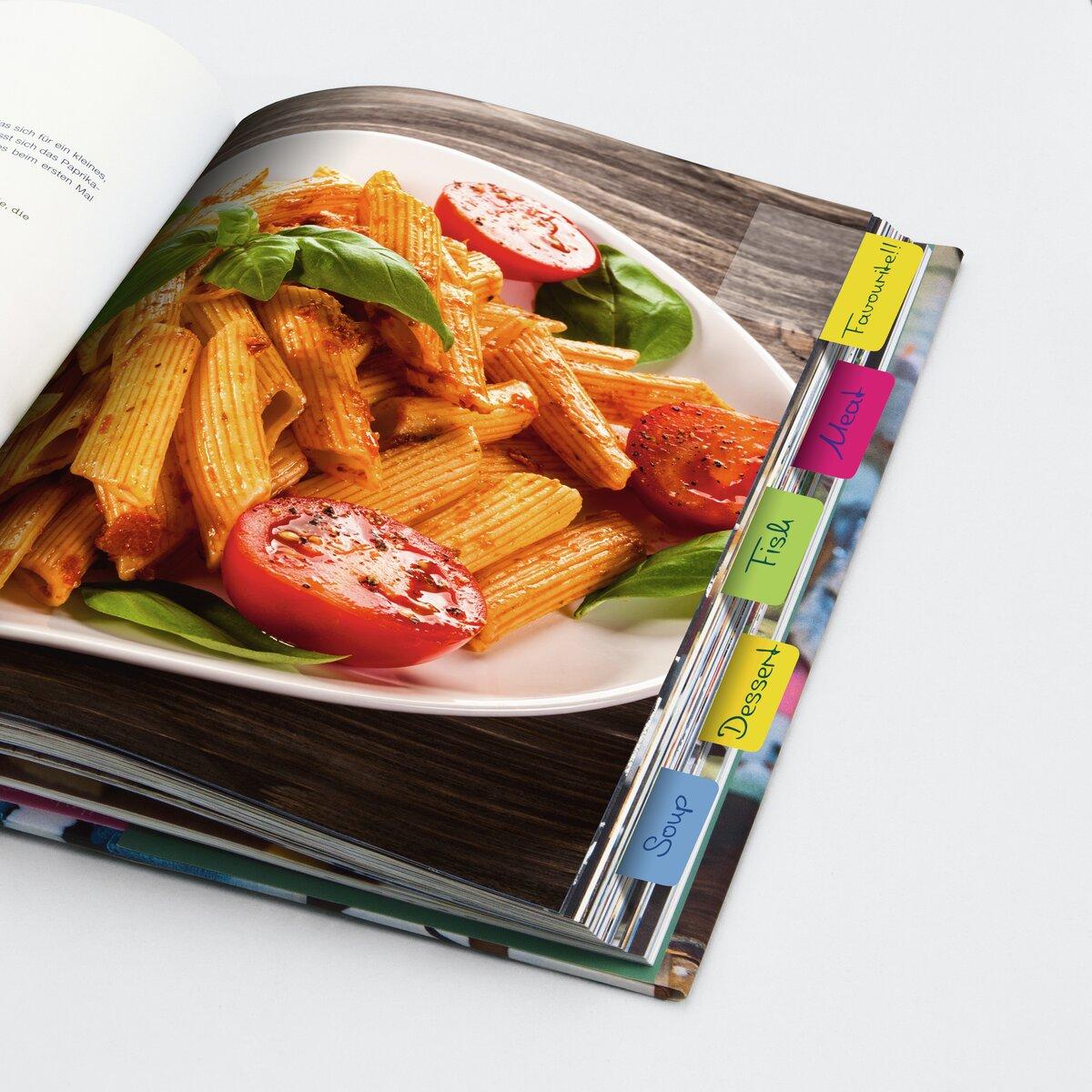 Pasta mit Tomaten und Basilikum auf Teller; geöffnetes Kochbuch mit Registerkarten