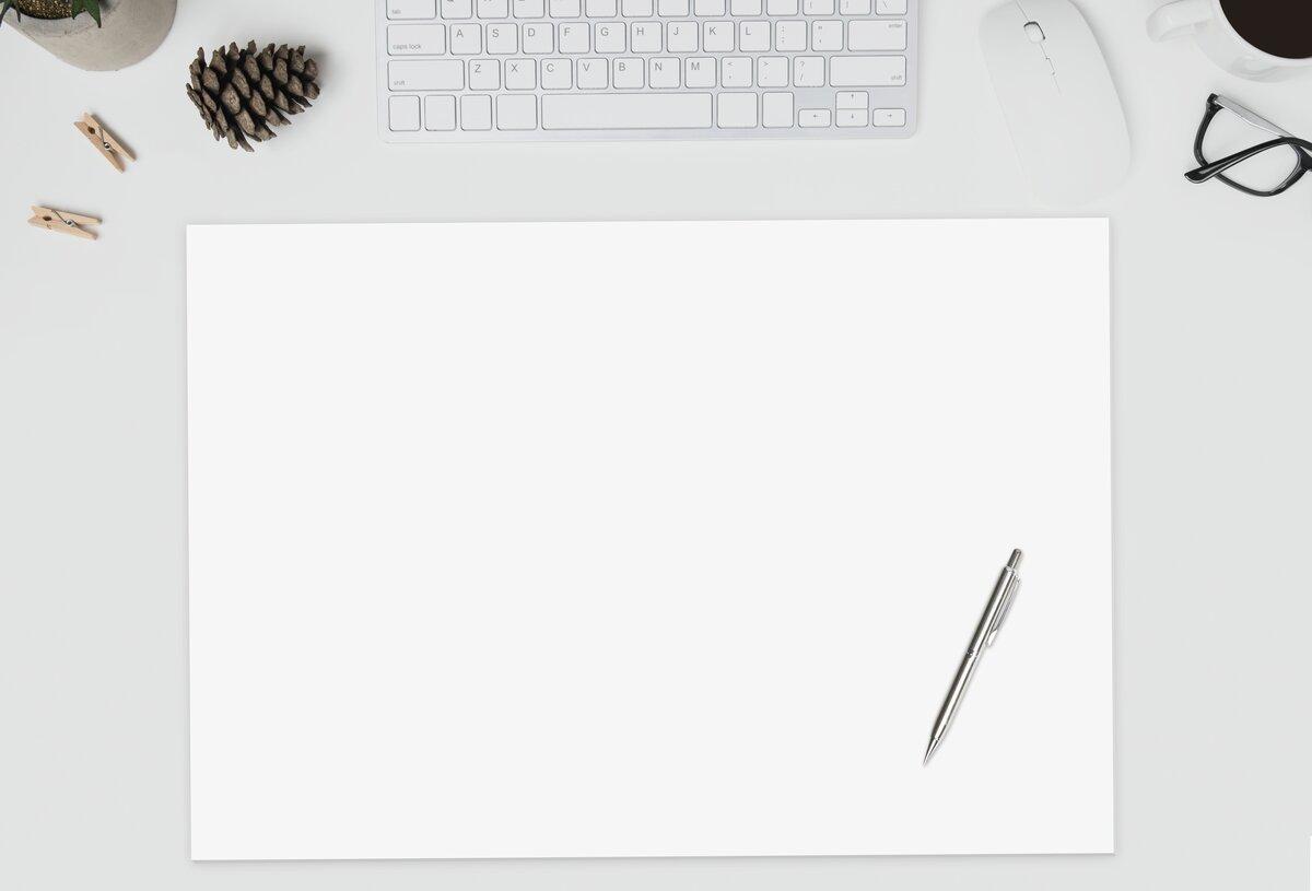 Schreibtisch mit Tastatur, Tasse, Brille, Blättern, Stift und leerem Papier