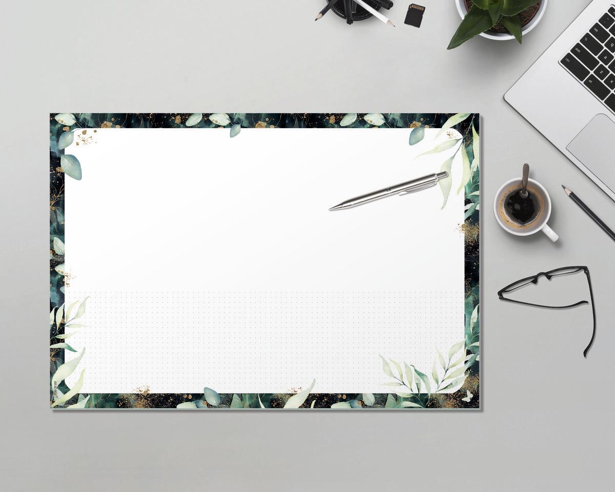 Schreibtisch mit Laptop, Notizblock mit Pflanzenrand, Stift, Brille und Kaffeetasse