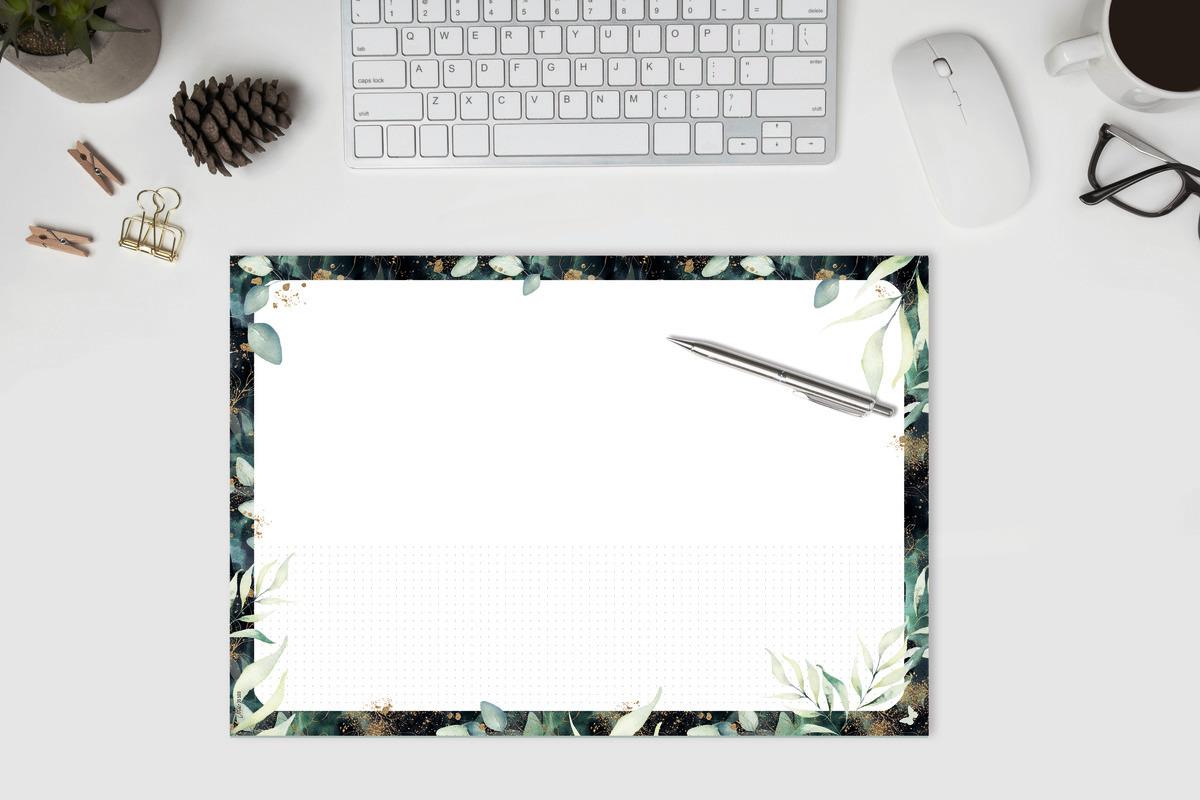 Schreibtisch mit Tastatur, Maus, Brille, Tannenzapfen und dekoriertem Notizblock