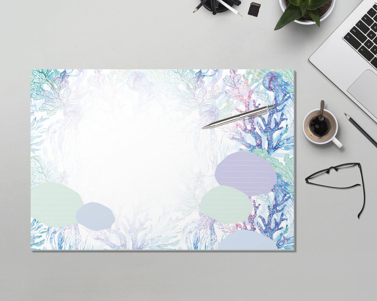 Notizblock mit buntem Korallenmuster, daneben Laptop, Brille und Kaffeetasse