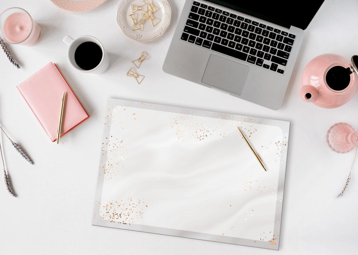 Laptop und Notizbuch auf einem Schreibtisch mit Kaffeetasse und Teekanne