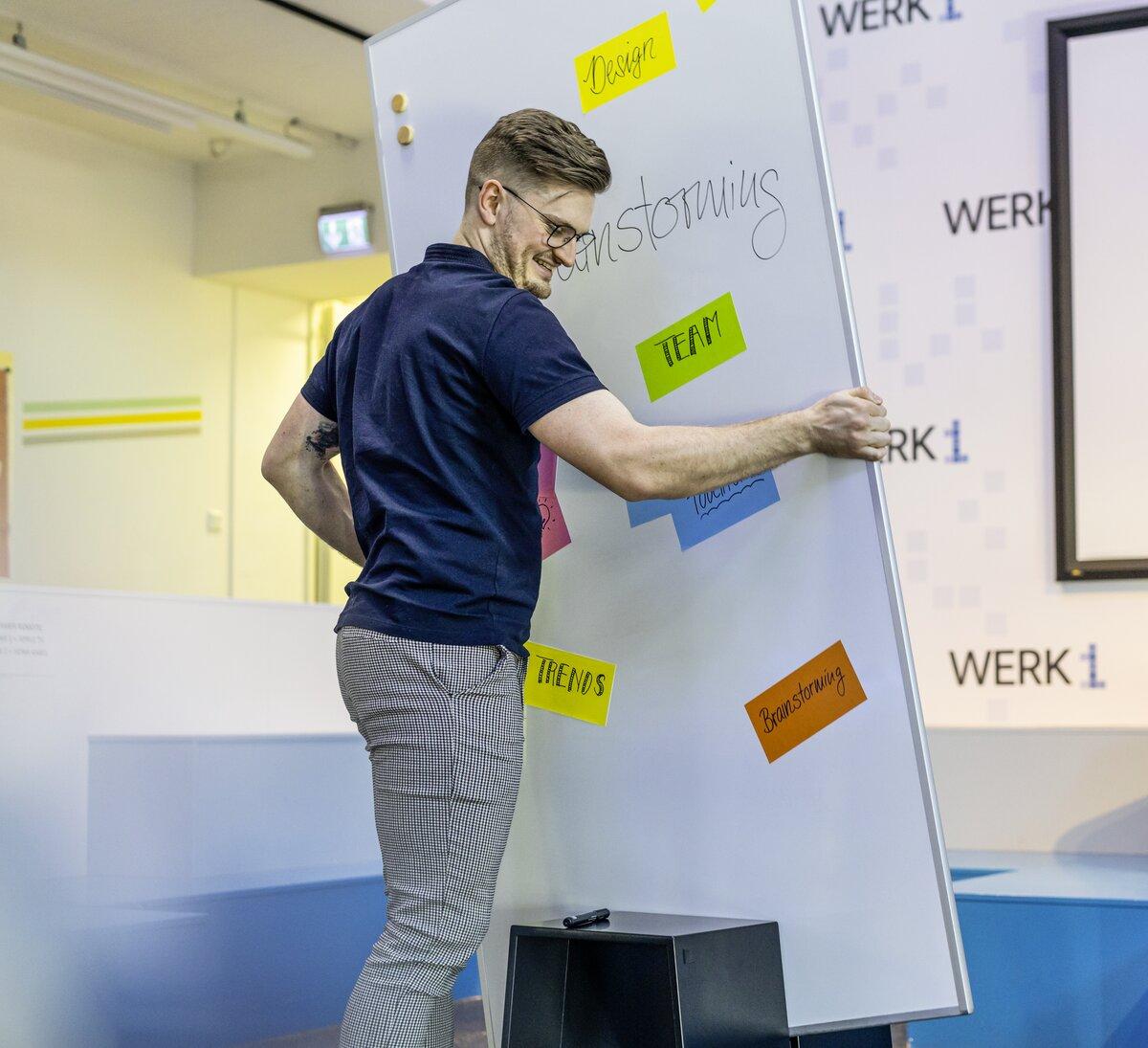 Person arranging colorful notes on a blackboard