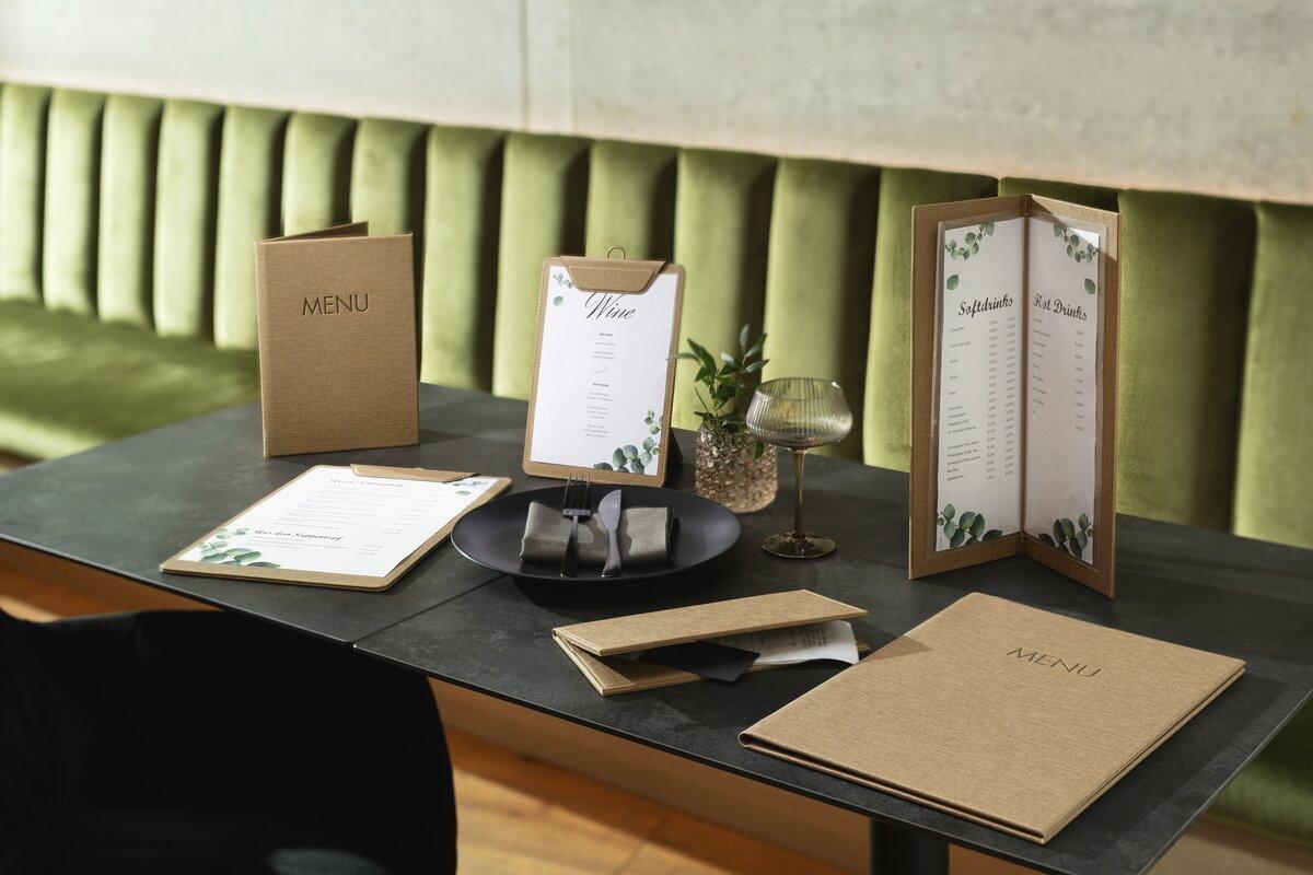 Menüs und Weinkarten auf Tisch mit grüner Polsterbank
