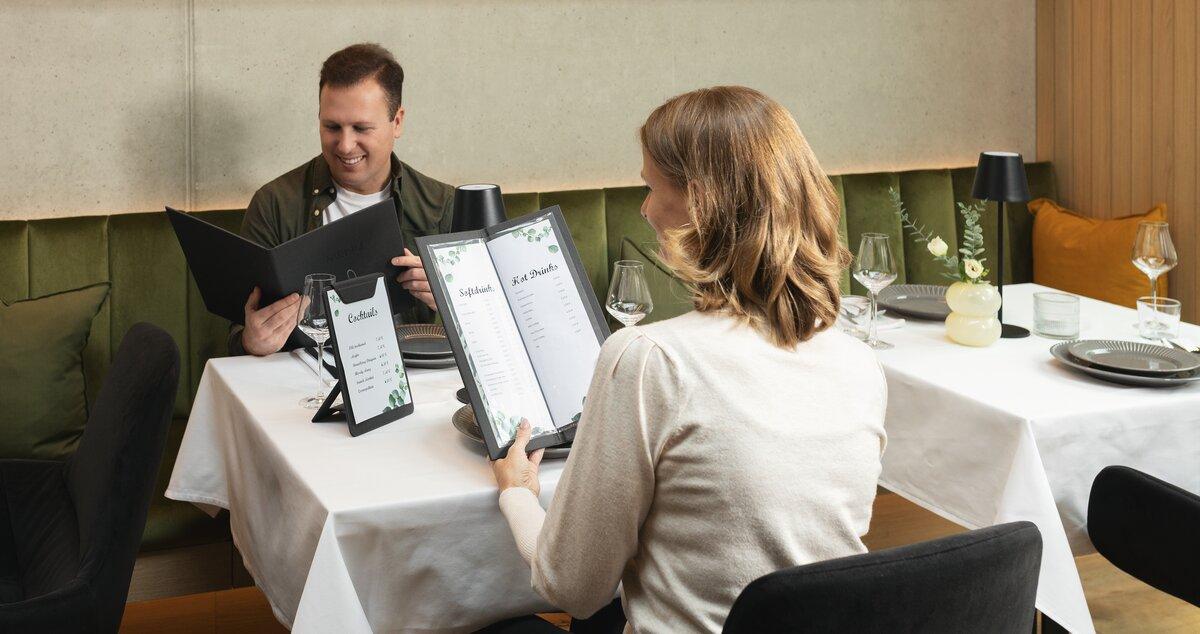 Zwei Personen lesen Speisekarten an einem Tisch im Restaurant