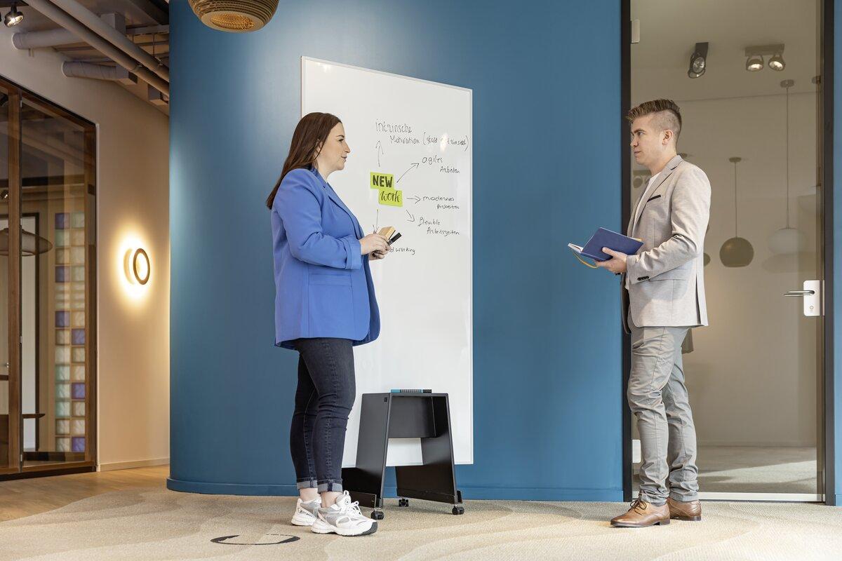 Personen diskutieren an einem Whiteboard