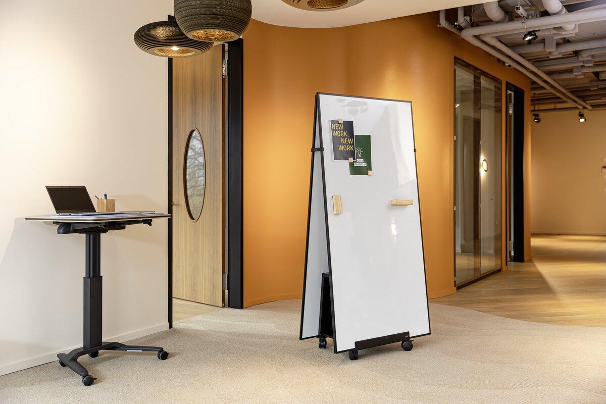 Standing desk with laptop, writable blackboard in modern office corridor