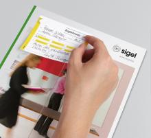 Hand hebt Notizblatt von Broschüre ab