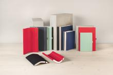 Verschiedene bunte Notizbücher stehen und liegen auf einem hellen Tisch