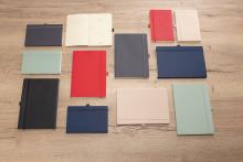 Notizbücher in verschiedenen Farben auf Holztisch angeordnet