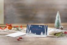 Weihnachtskarte mit Schneelandschaft und Frohe Weihnachten, im Hintergrund Tannendeko