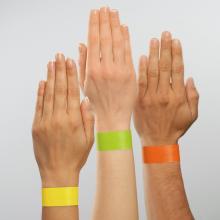 Three hands held up with different colored paper wristbands: yellow, green, orange