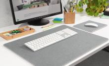 Monitor und Tastatur auf einem Schreibtisch Büroaccessoires und Pflanze im Hintergrund