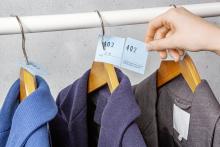 Jacken an Kleiderbügeln mit Garderobenmarken Hand hält eine Marke mit Nummer 402