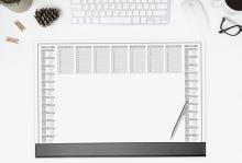 Schreibtisch mit Kalender, Tastatur, Maus, Brille und Tasse