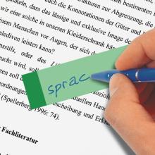 Grüner Notizzettel auf Textseite, Hand schreibt