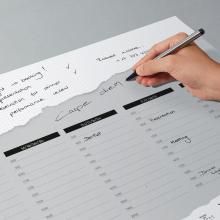 Hand schreibt auf Notizblock Agenda mit Terminen