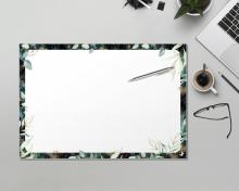 Schreibtisch mit Laptop, Notizblock mit Pflanzenrand, Stift, Brille und Kaffeetasse