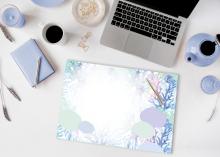 Laptop auf Schreibtisch mit Notizbuch, Tasse Kaffee, und bemaltem Papier