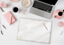 Laptop und Notizbuch auf einem Schreibtisch mit Kaffeetasse und Teekanne