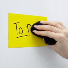 Hand wipes text from yellow sign