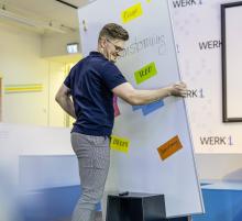 Person arranging colorful notes on a blackboard
